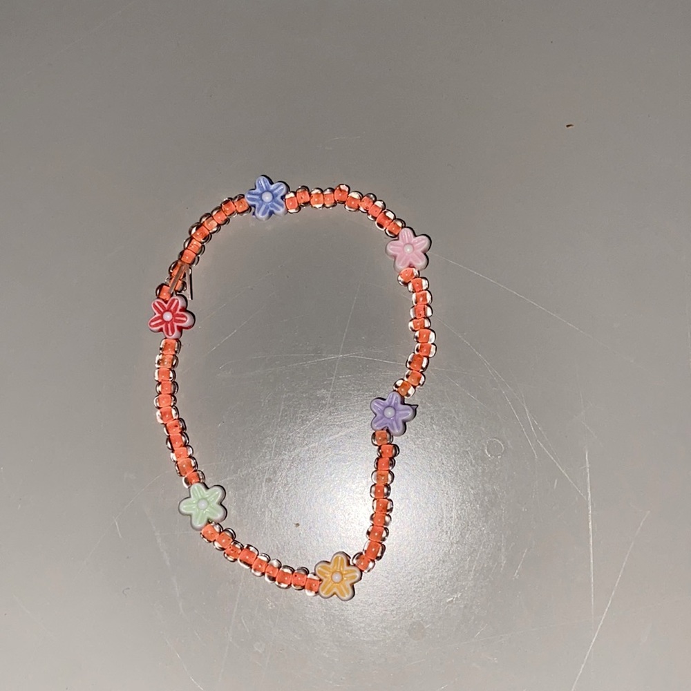 Orange beaded bracelet with six different flowers.